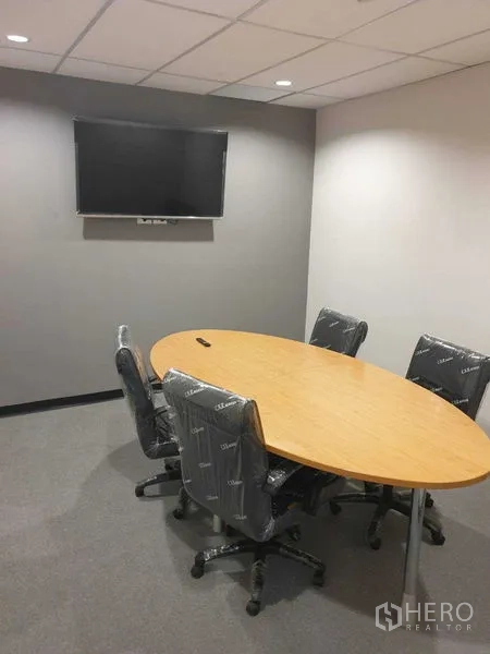 Office Space for rent in Chatuchak, Bangkok - Small meeting room with oval table, swivel chairs and wall-mounted TV.