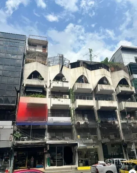 Shophouse for sale in Watthana, Bangkok - Multi-storey shophouse row in the Sukhumvit area with arched balconies, rooftop terraces and street-front shops under a blue sky.