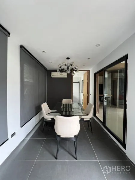 联排别墅 出租在Saphan Sung, Bangkok - 明亮餐厅，玻璃餐桌、现代吊灯与卷帘。