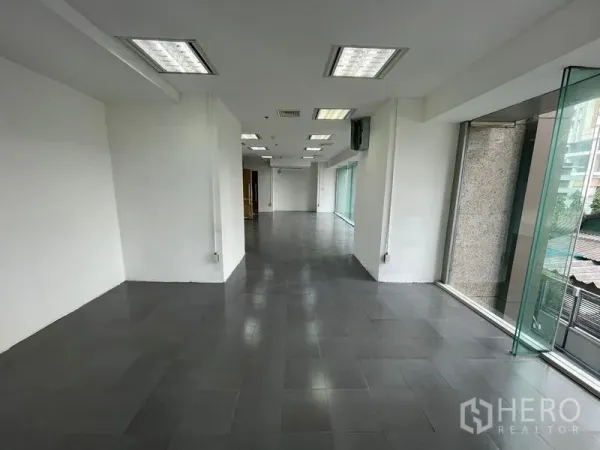 สำนักงาน ให้เช่า - มุมสว่างของสำนักงานเปล่า ผนังสีขาว เสา และแนวหน้าต่างยาว