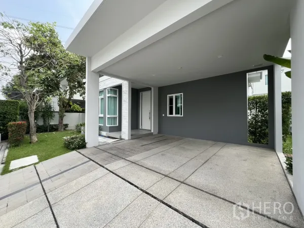 独立式住宅 出租在Prawet, Bangkok - 带顶双车位车棚，旁有草坪与入户门。