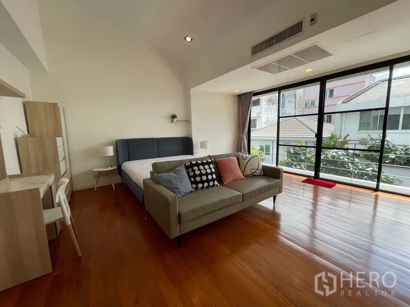 Townhouse for rent in Khlong Toei, Bangkok - Oversized master bedroom with sofa seating and wall-to-wall sliding doors.