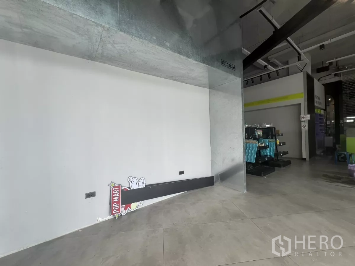 พื้นที่ขายปลีก ให้เช่า - มุมแสดงสินค้ากรุกระเบื้องโลหะและผนังสีขาว ข้างโถงขายของเพดานสไตล์ลอฟต์.