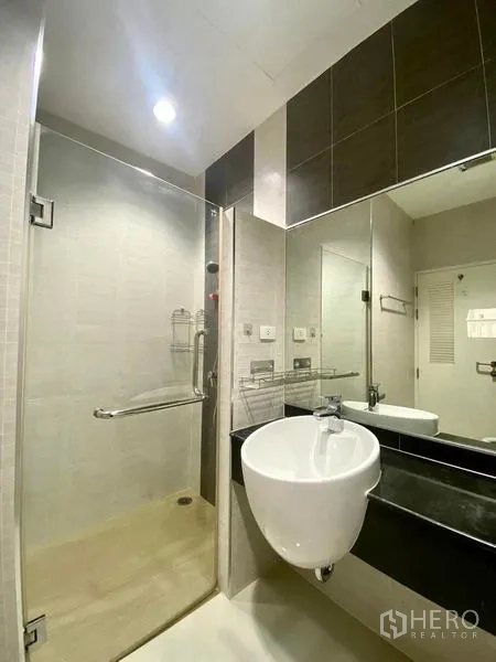 คอนโด ให้เช่าหรือขายในBang Kapi, Bangkok - ห้องน้ำสมัยใหม่พร้อมตู้ชาวเวอร์กระจก อ่างล้างหน้าทรงกลม และกระจกเงาบานใหญ่