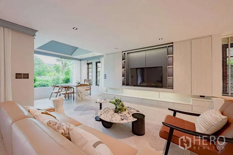 บ้าน ให้เช่าหรือขายในPhra Khanong, Bangkok - ห้องนั่งเล่นเปิดมุมมองสู่สนามหญ้าและผนังทีวีขนาดใหญ่