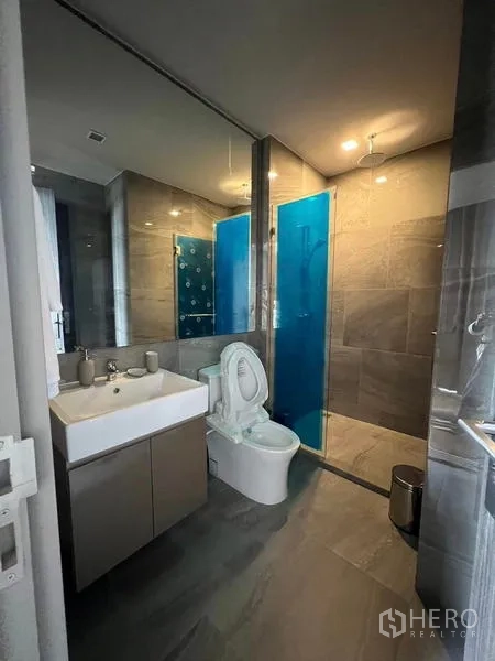 公寓 出租在Ratchathewi, Bangkok - 现代浴室，玻璃淋浴间、蓝色隔板与洗手台。