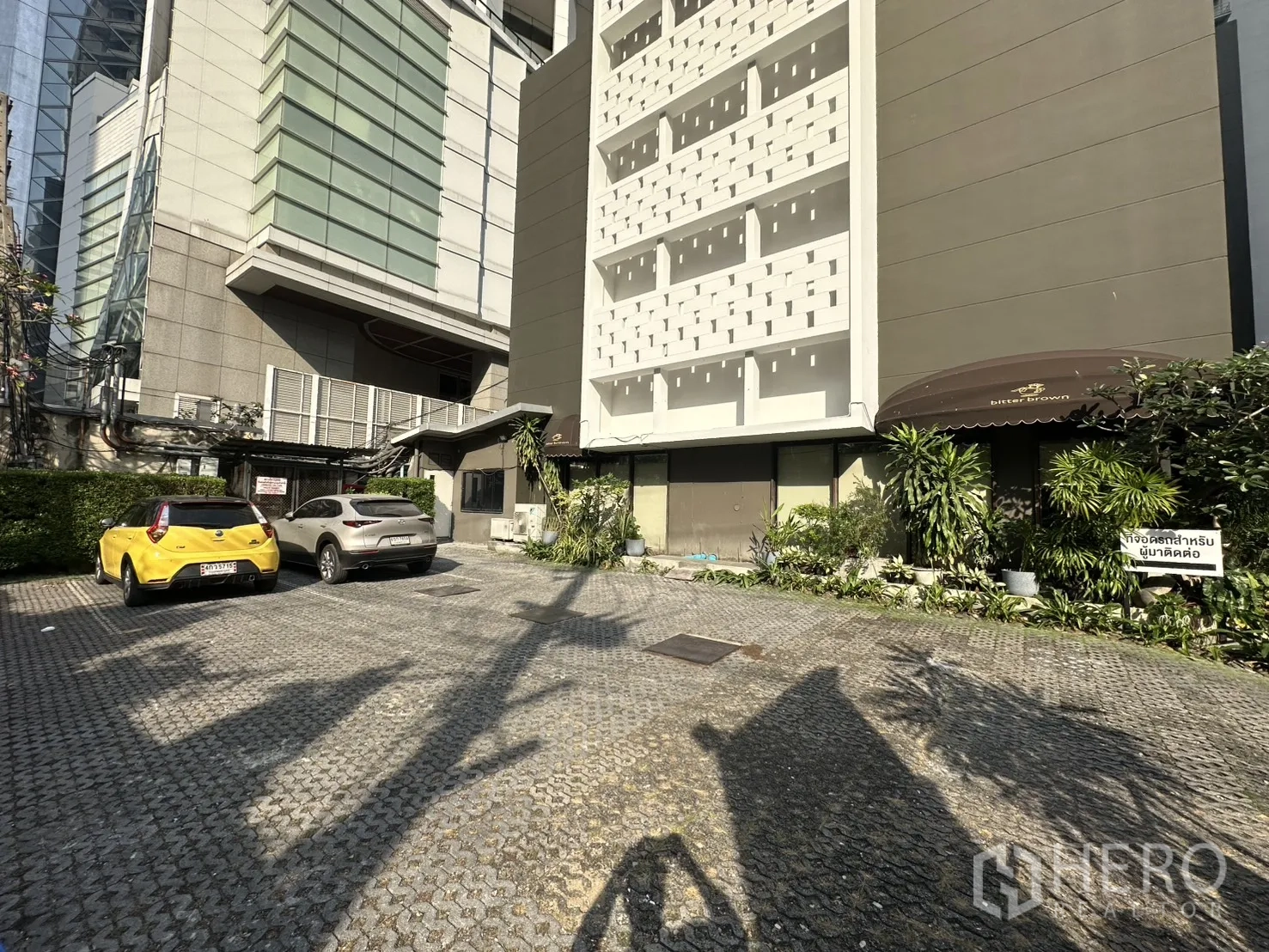 Retail Space for rent in Watthana, Bangkok - Building exterior with a wide paved forecourt offering car parking and neighboring high‑rises.