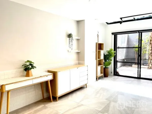 Townhouse for rent in Khlong Toei, Bangkok - Bright Ekkamai townhouse living area with skylight, built-in cabinets and sliding doors to a private patio.