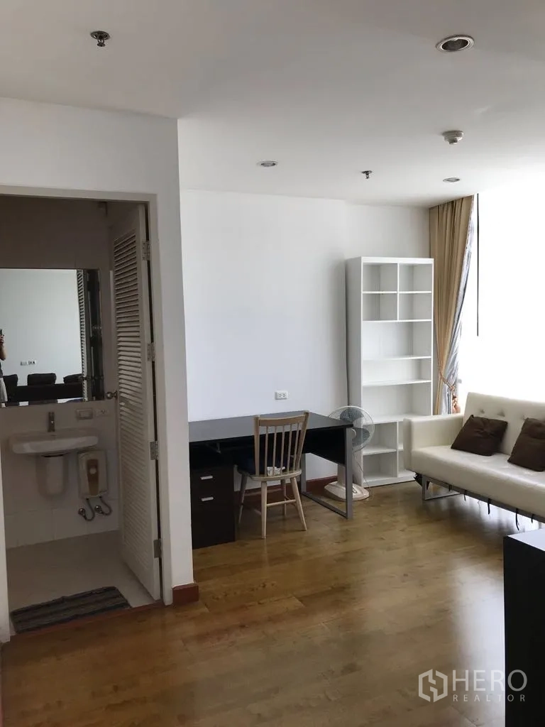 Condominium for rent in Watthana, Bangkok - Bright study corner with desk, white sofa and doorway to a guest bathroom