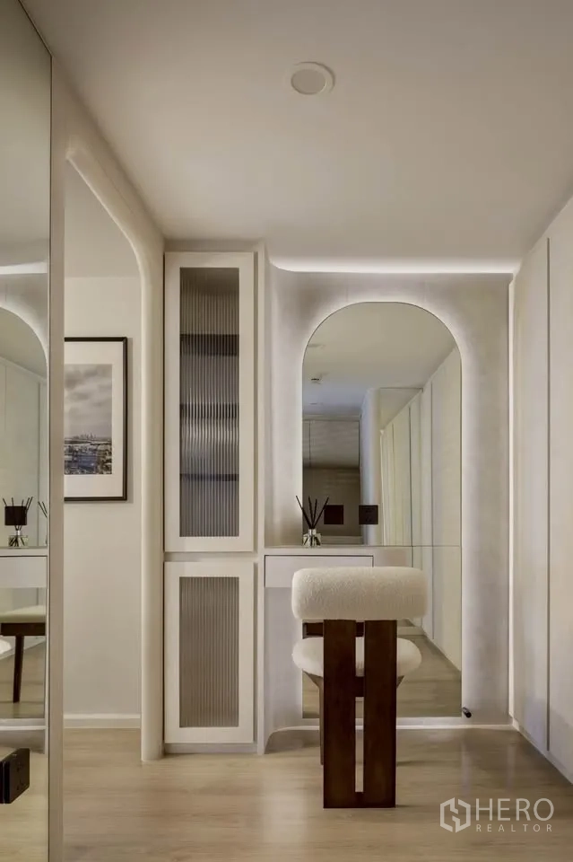Condominium for rent in Khlong Toei, Bangkok - Dressing area with arched mirror, soft lighting, and storage cabinets.