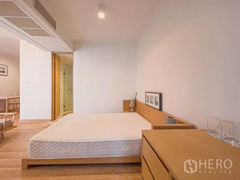 คอนโด ขายในWatthana, Bangkok - มุมมองจากห้องนอนไปยังพื้นที่นั่งเล่น เห็นลิ้นชัก โคมไฟหัวเตียง และทางเข้าห้องน้ำ