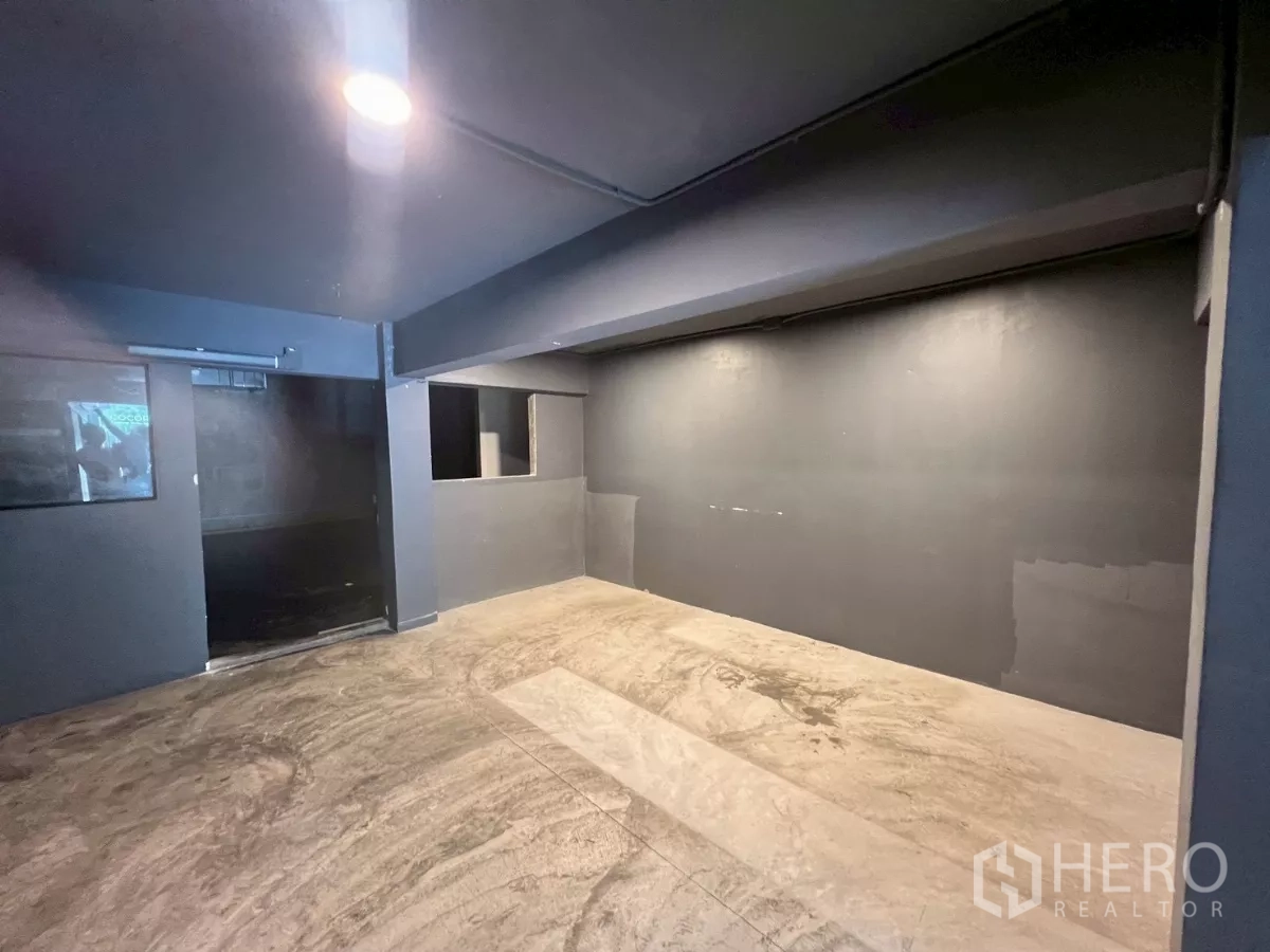 อาคารพาณิชย์ ให้เช่าในWatthana, Bangkok - ห้องโทนเทาเข้มโล่ง พร้อมไฟฝังและพื้นคอนกรีต.