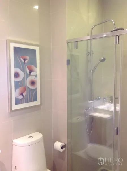 Condominium for rent or sale in Watthana, Bangkok - Modern bathroom featuring a glass-enclosed shower and toilet.