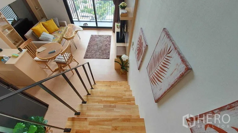 Condominium for rent in Watthana, Bangkok - View from staircase over loft-style living area with balcony and abundant natural light.