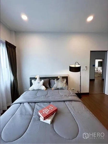 Detached House for rent or sale in Bang Phli, Samut Prakan - Cozy secondary bedroom with gray bedding, bedside lamp and window drapes.