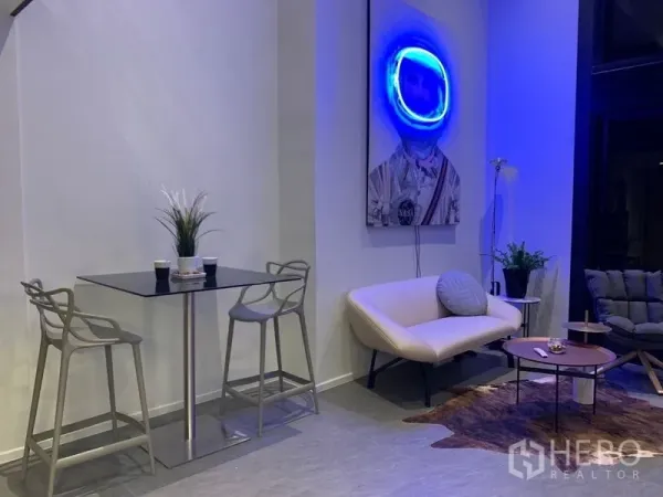 公寓 出租在Bang Rak, Bangkok - 挑高客厅，沙发与餐桌，墙上霓虹艺术装饰。