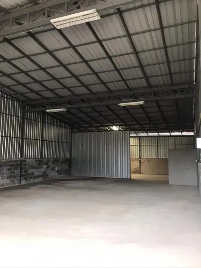 Warehouse for rent in Bang Kapi, Bangkok - Spacious warehouse interior with high steel truss roof, fluorescent lighting and smooth concrete floor.