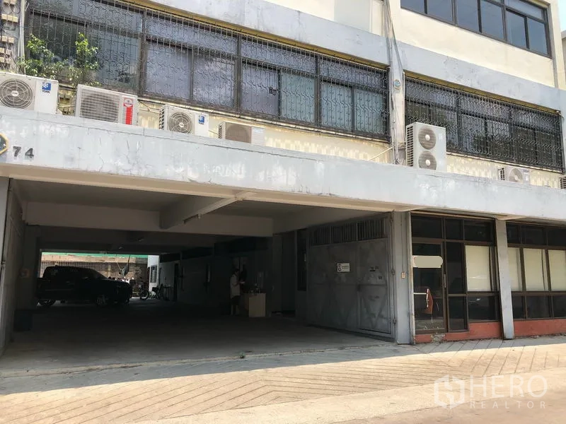 Warehouse for rent in Chatuchak, Bangkok - Covered ground-level loading bay and parking area with a metal gate at the front of the warehouse.