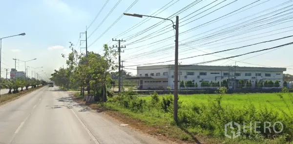 Land for sale in Lat Lum Kaeo, Pathum Thani - Roadside scene with a modern factory and green fields opposite the land along the main carriageway.