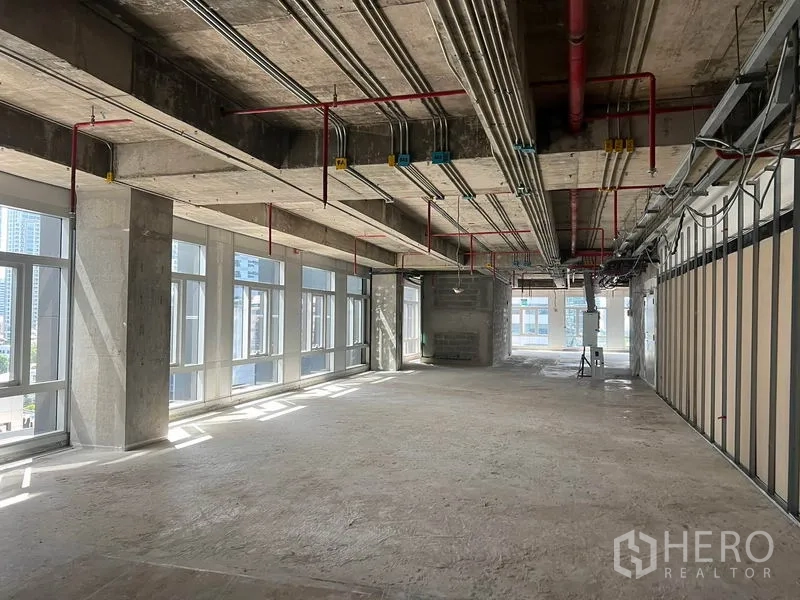 พื้นที่ขายปลีก ให้เช่าในBang Rak, Bangkok - พื้นที่ค้าปลีกแบบโถงโล่งสภาพเปลือกอาคาร เพดานคอนกรีตเปลือยและงานระบบ พร้อมหน้าต่างบานใหญ่รับแสงธรรมชาติ.