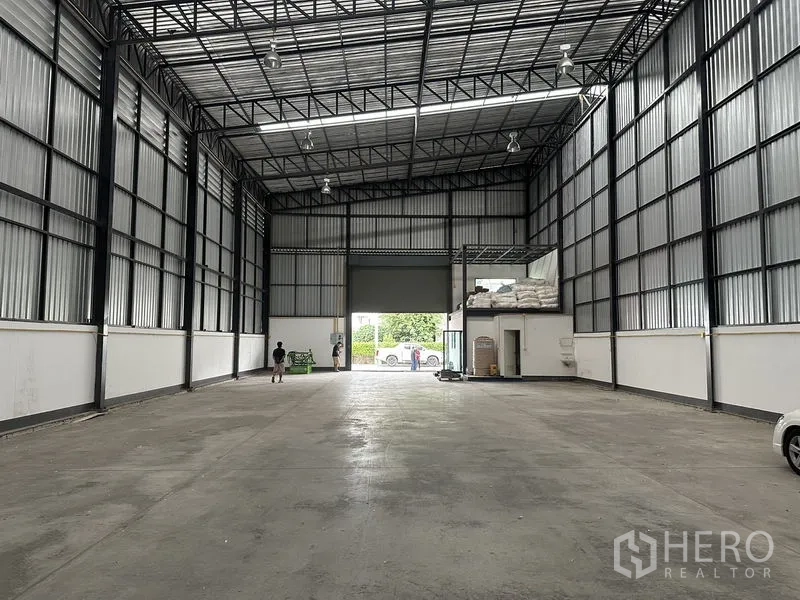 货栈 出租在Samut Prakan - 从仓库内部望向大型卷帘门与带雨棚的装卸口。