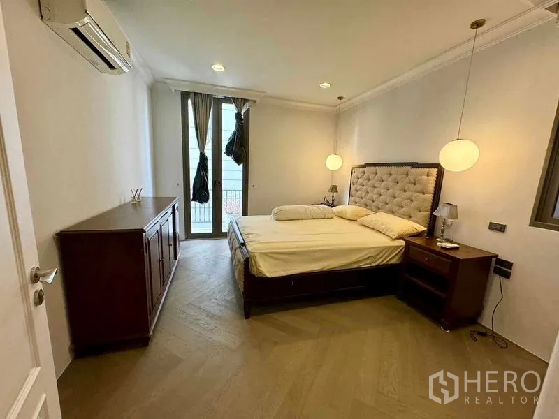 ทาวน์เฮาส์ ให้เช่าในWatthana, Bangkok - ห้องนอนอบอุ่น หัวเตียงบุตะปุ่ม โคมแขวน และประตูออกระเบียง.