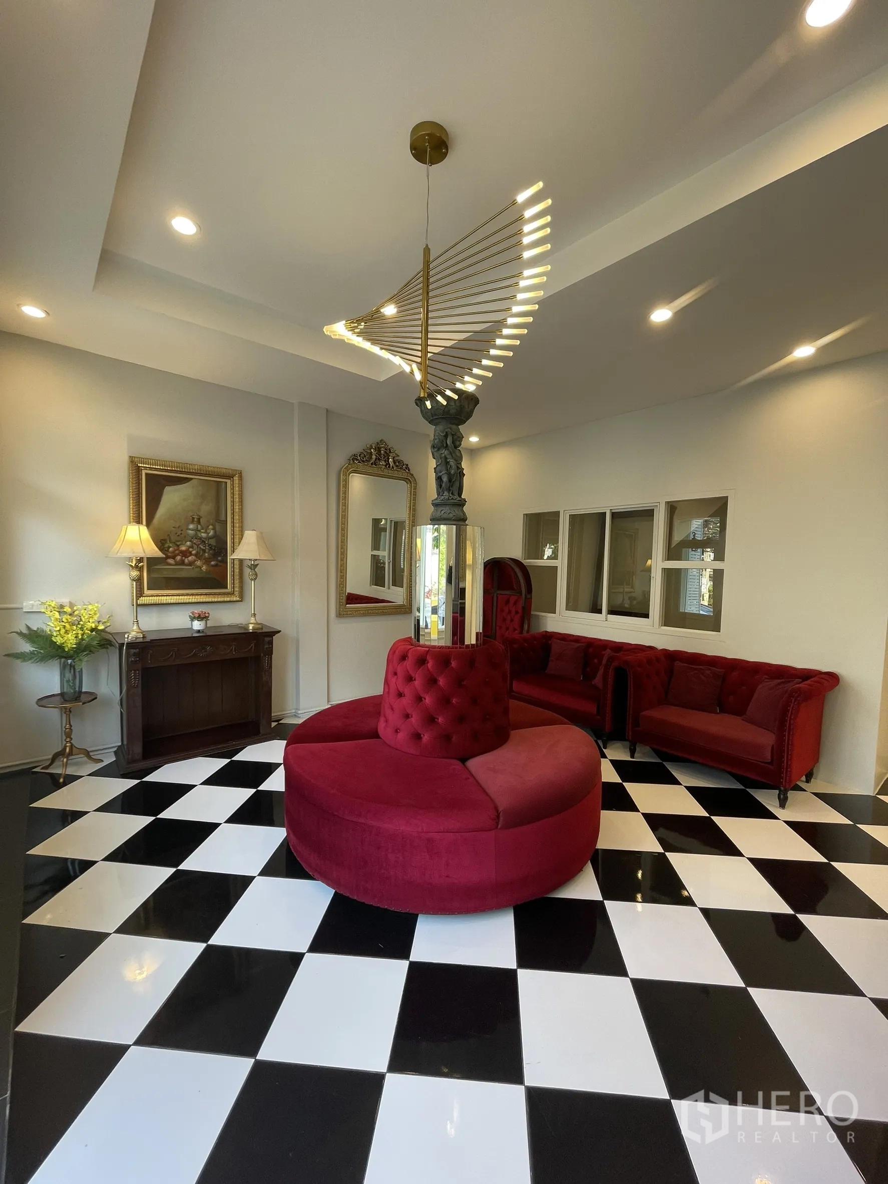 Shophouse for rent in Bang Kapi, Bangkok - Lounge area with round tufted seat, framed art, mirrors and black‑and‑white tiles.