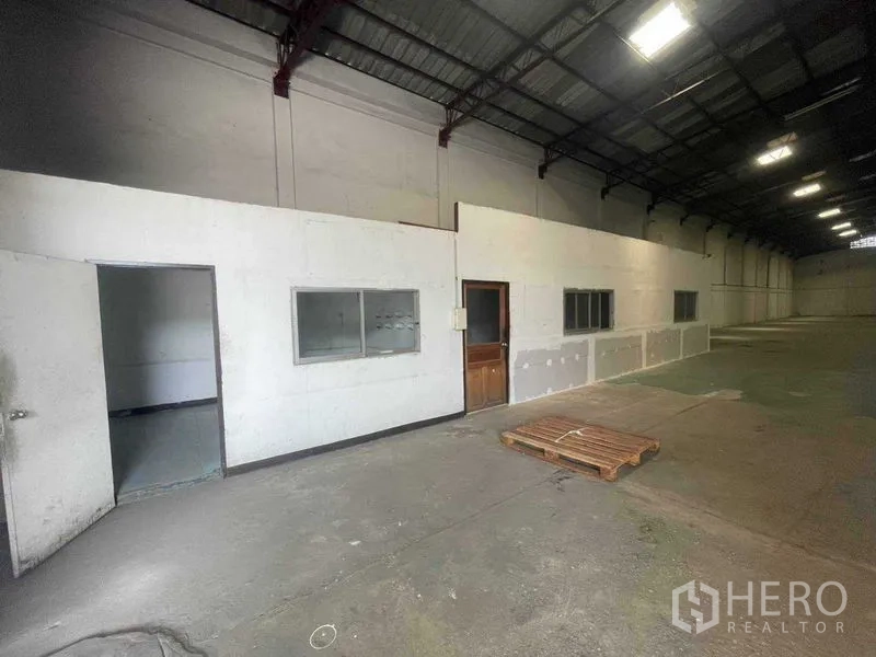 Warehouse for rent in Khlong Toei, Bangkok - Side view of warehouse office rooms with doors and windows beside a large loading space.