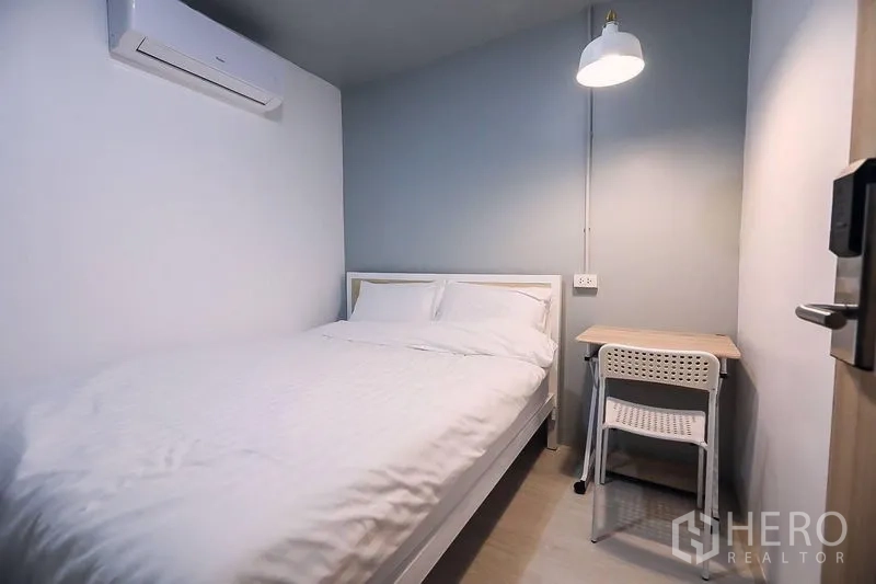 อาคารพาณิชย์ ให้เช่าในKhlong Toei, Bangkok - ห้องนอนกะทัดรัดมีเครื่องปรับอากาศ เตียงคู่ โต๊ะทำงาน และโคมไฟผนัง