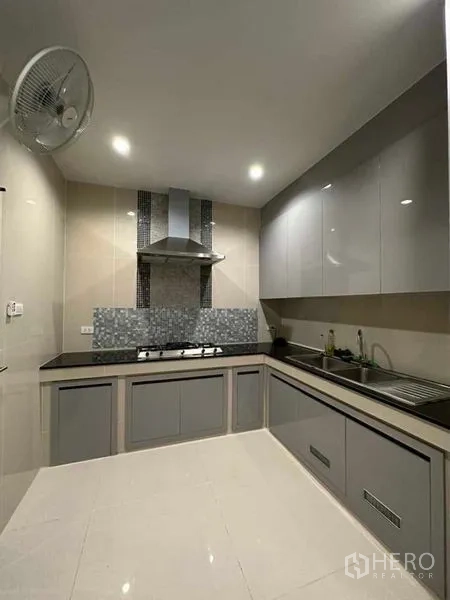 Detached House for sale in Prawet, Bangkok - Enclosed kitchen with grey cabinetry, gas hob, range hood and stone countertops.