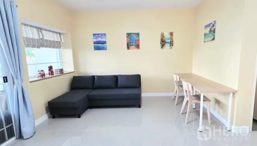 Townhouse for rent in Bang Bo, Samut Prakan - Open-plan lounge with L-shaped sofa, window seat and neutral walls.