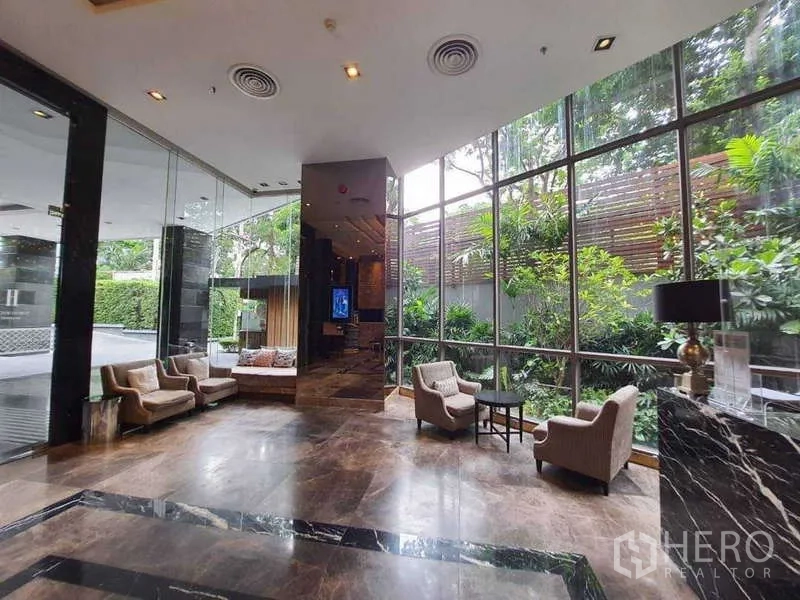 公寓 出售在Watthana, Bangkok - 高挑玻璃与大理石地面的雅致大堂，面向花园景观。