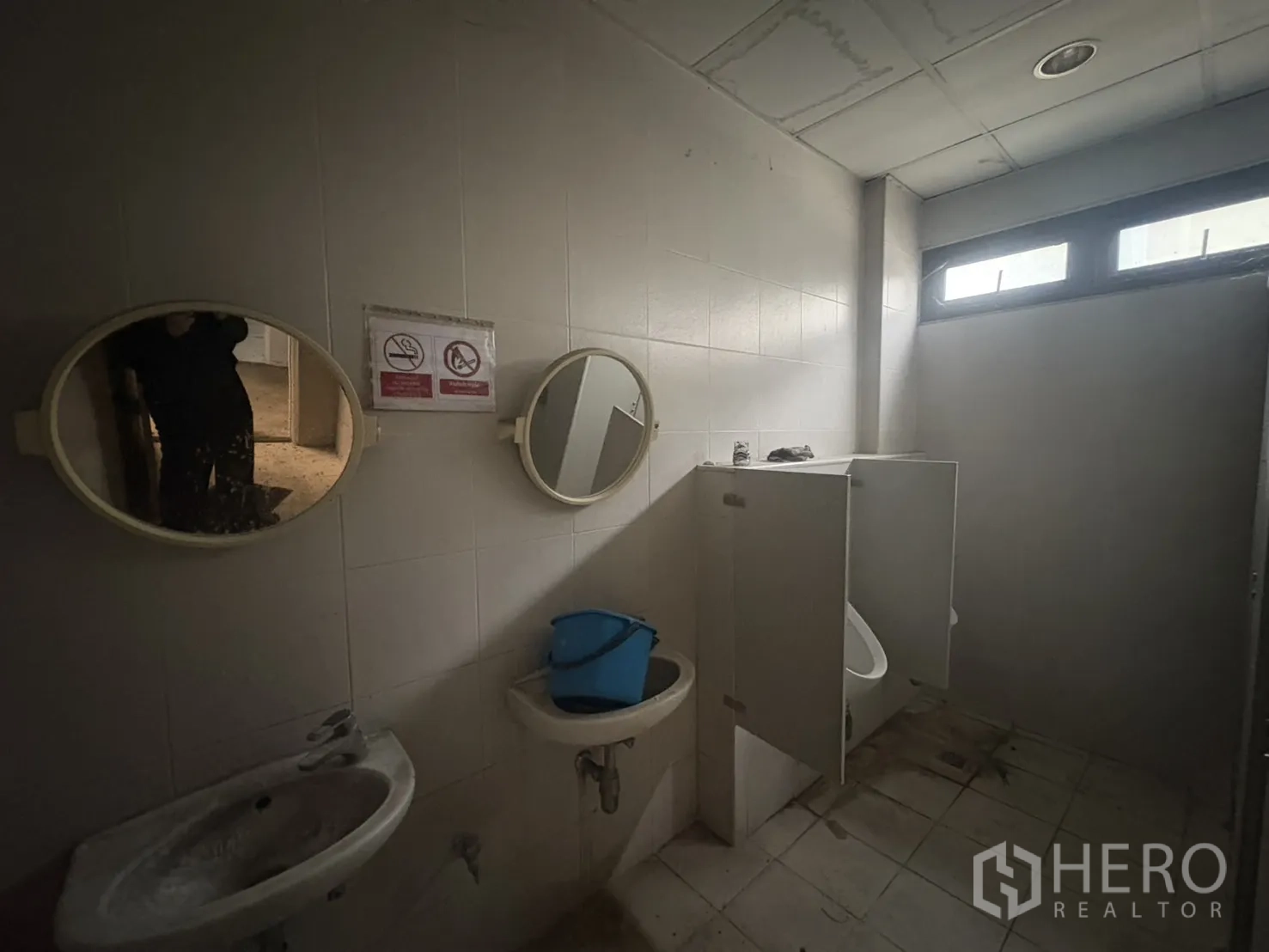 Factory for rent or sale in Samut Prakan - Internal wall of the warehouse with multiple windows and a personnel door.