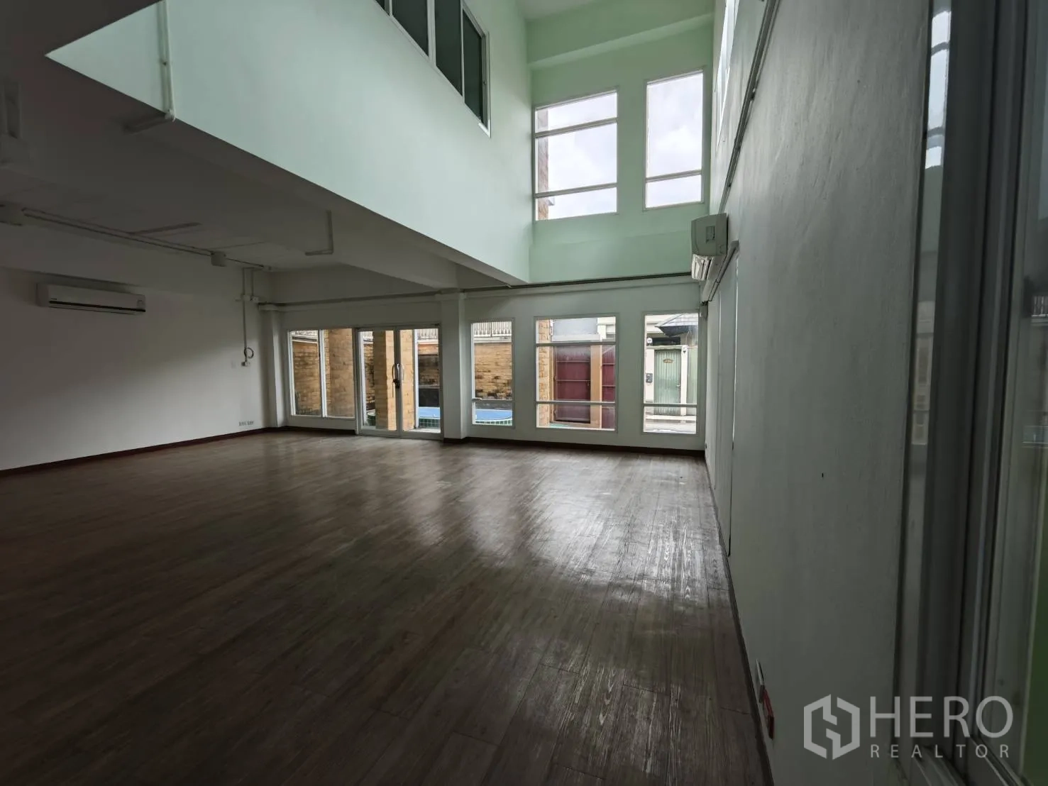 Office Space for rent in Prawet, Bangkok - Double-height workspace with tall windows and a glass door bringing natural light.