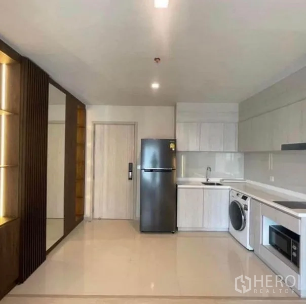Condominium for rent or sale - Open kitchen with white cabinetry, fridge, washer and microwave.