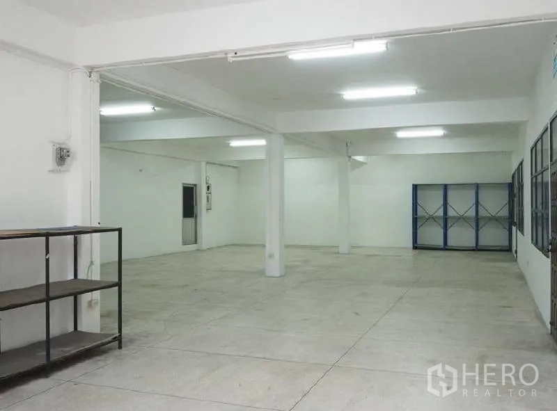 Warehouse for rent in Bang Kapi, Bangkok - Clean storage area with shelving, white walls, columns and bright lighting.