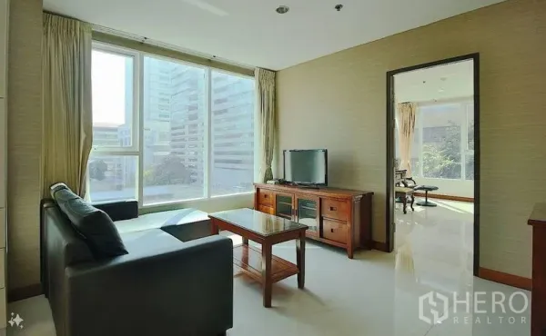 Condominium for sale in Watthana, Bangkok - Living area with TV console, sofa and floor-to-ceiling windows overlooking the Asok business district.