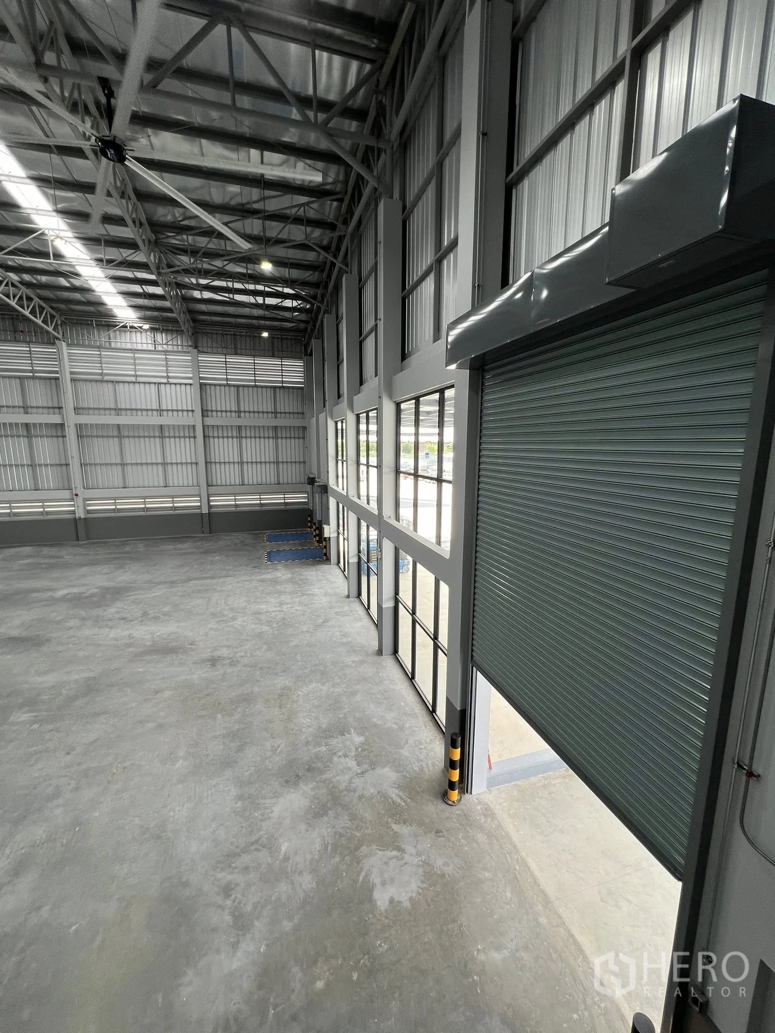 Warehouse for rent in Phra Pradaeng, Samut Prakan - Close-up of a motorized roller shutter and high windows at the loading bay.