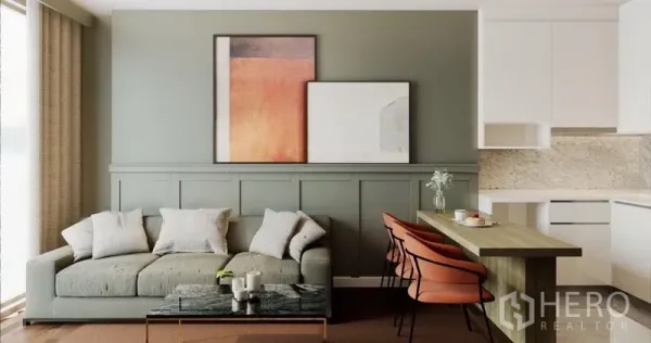 公寓 出租在Phra Khanong, Bangkok - 现代公寓客厅，鼠尾草绿特色墙，舒适沙发，大理石茶几，吧台与白色厨房。