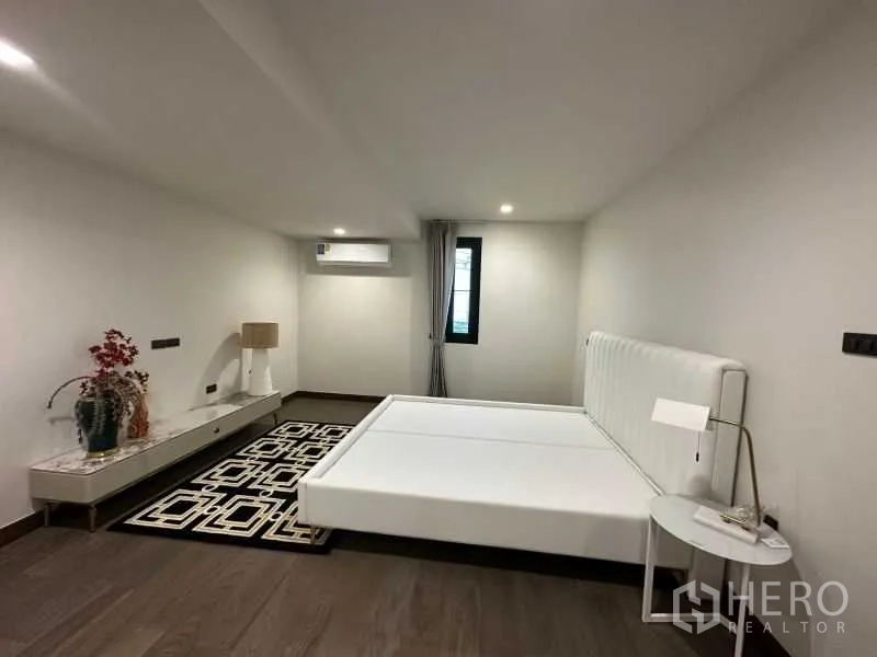 Detached House for rent in Suan Luang, Bangkok - Minimalist bedroom with white bed frame, side table and wood floors.