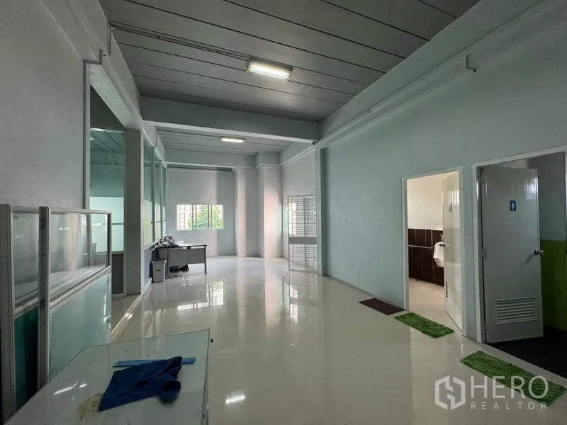 Warehouse for rent or sale in Chon Buri - Ground-floor workspace showing restroom access and natural light from windows.