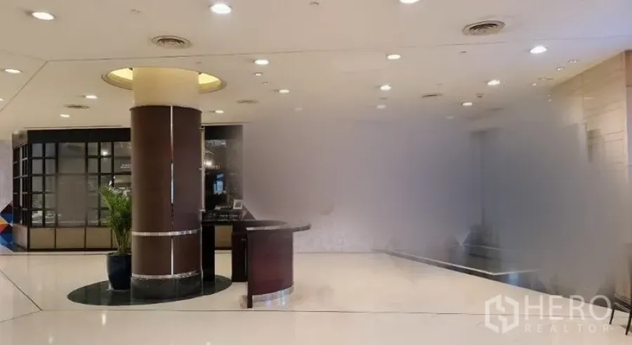 零售空间 出租在Pathum Wan, Bangkok - 室内零售大堂，亮白地面、嵌入式筒灯天花、圆形立柱与接待台。