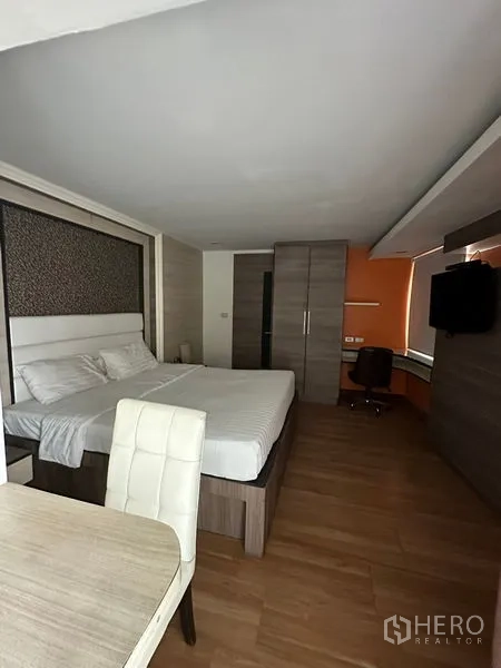 Apartment for rent in Khlong Toei, Bangkok - Studio room with desk, wardrobe, wall-mounted TV and large window.