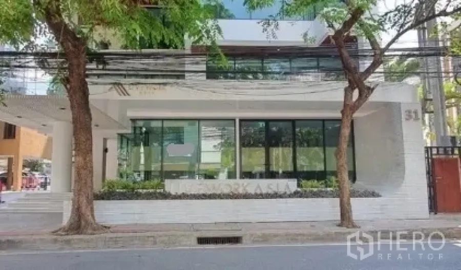 Retail Space for rent in Khlong Toei, Bangkok - Full frontage of a modern building showing a ground-floor glass retail space, mature street trees, and a city street view.