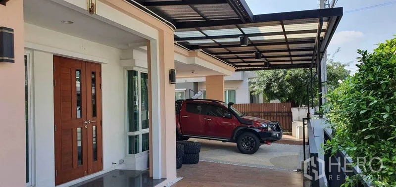 บ้าน ขายในKhan Na Yao, Bangkok - ด้านหน้าบ้านพร้อมประตูไม้สองบานและที่จอดรถมีหลังคากว้าง