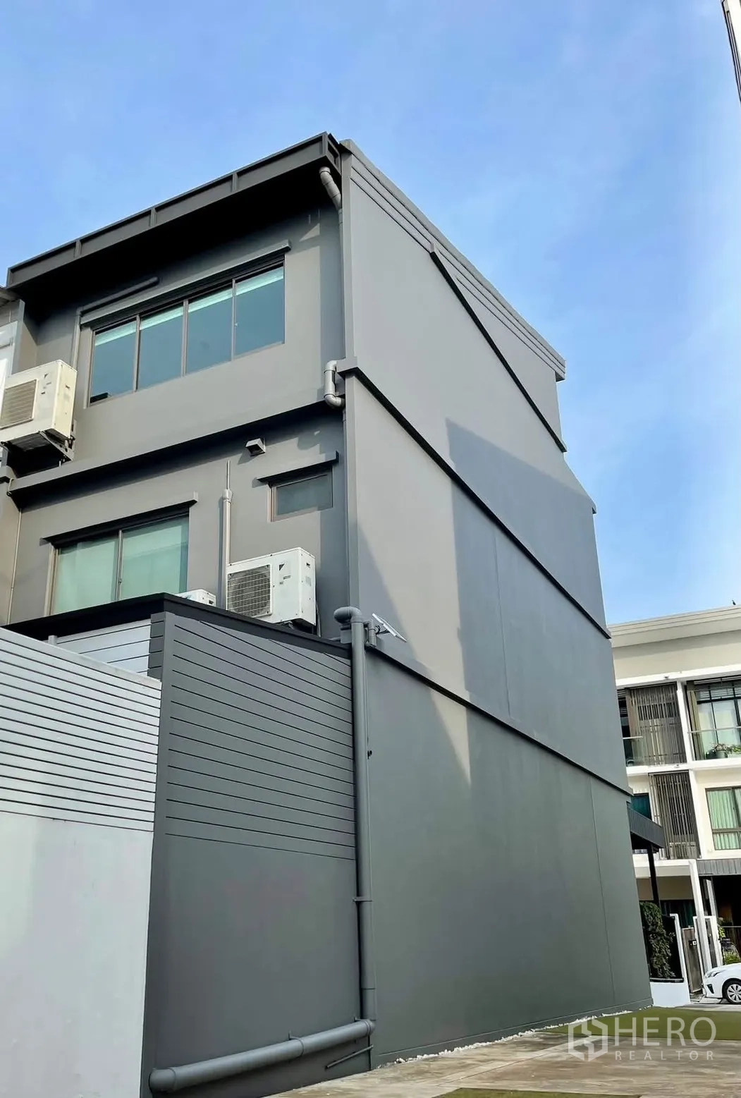 Townhouse for rent in Lat Phrao, Bangkok - Side exterior of three-storey townhouse with windows and AC units.