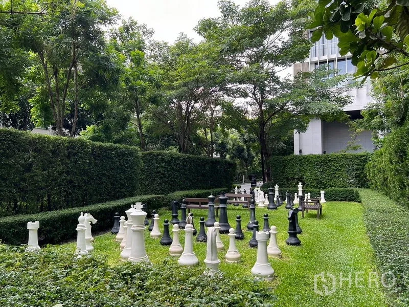 คอนโด ขาย - สนามหญ้าพร้อมหมากรุกยักษ์ รายล้อมด้วยแนวพุ่มไม้และต้นไม้