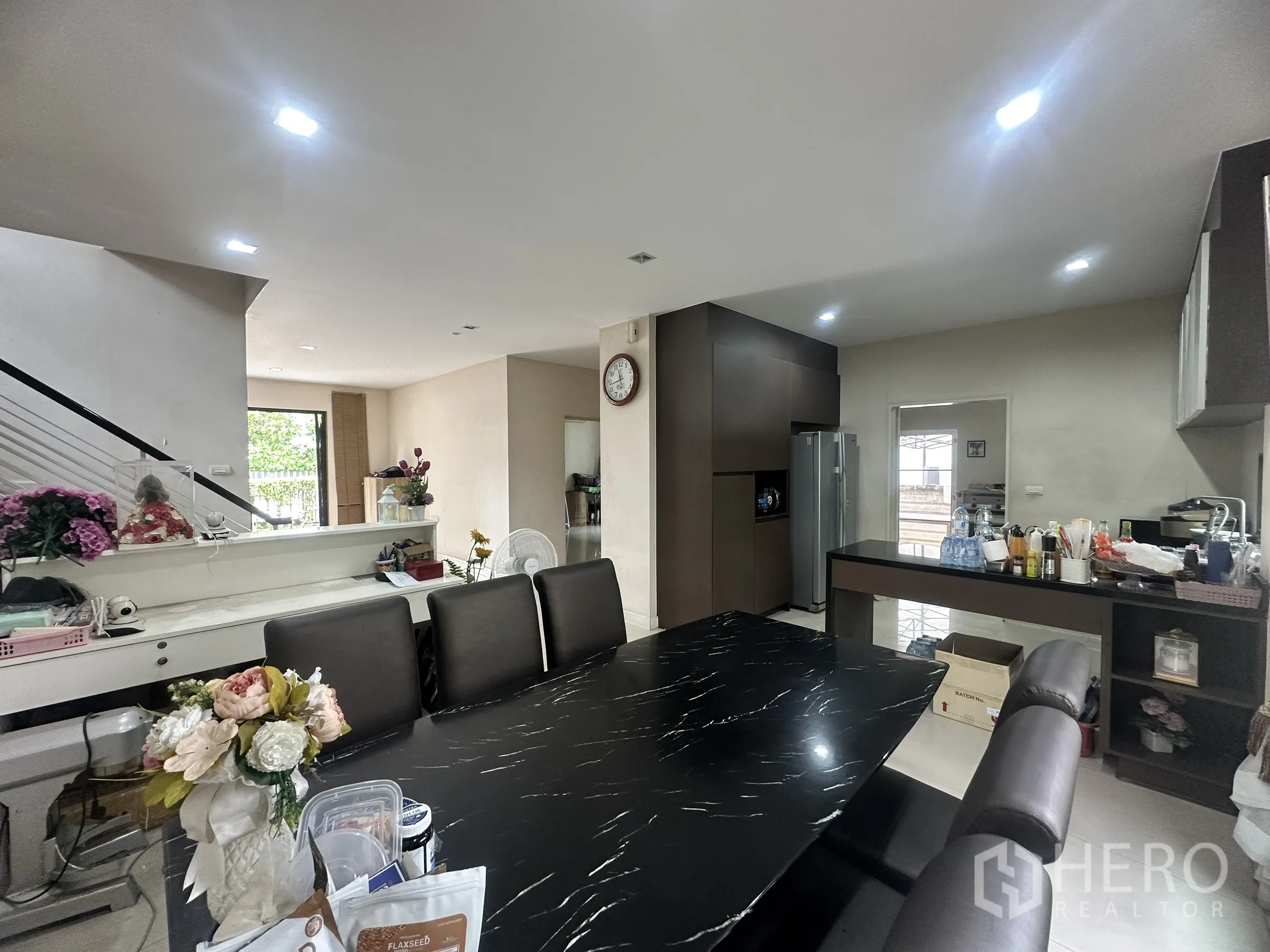 Detached House for sale in Pak Kret, Nonthaburi - Dining area beside open pantry kitchen with dark table and cabinetry.