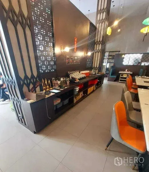 零售空间 出租在Watthana, Bangkok - 现代餐饮区，装饰镂空隔断、吊灯与服务台。