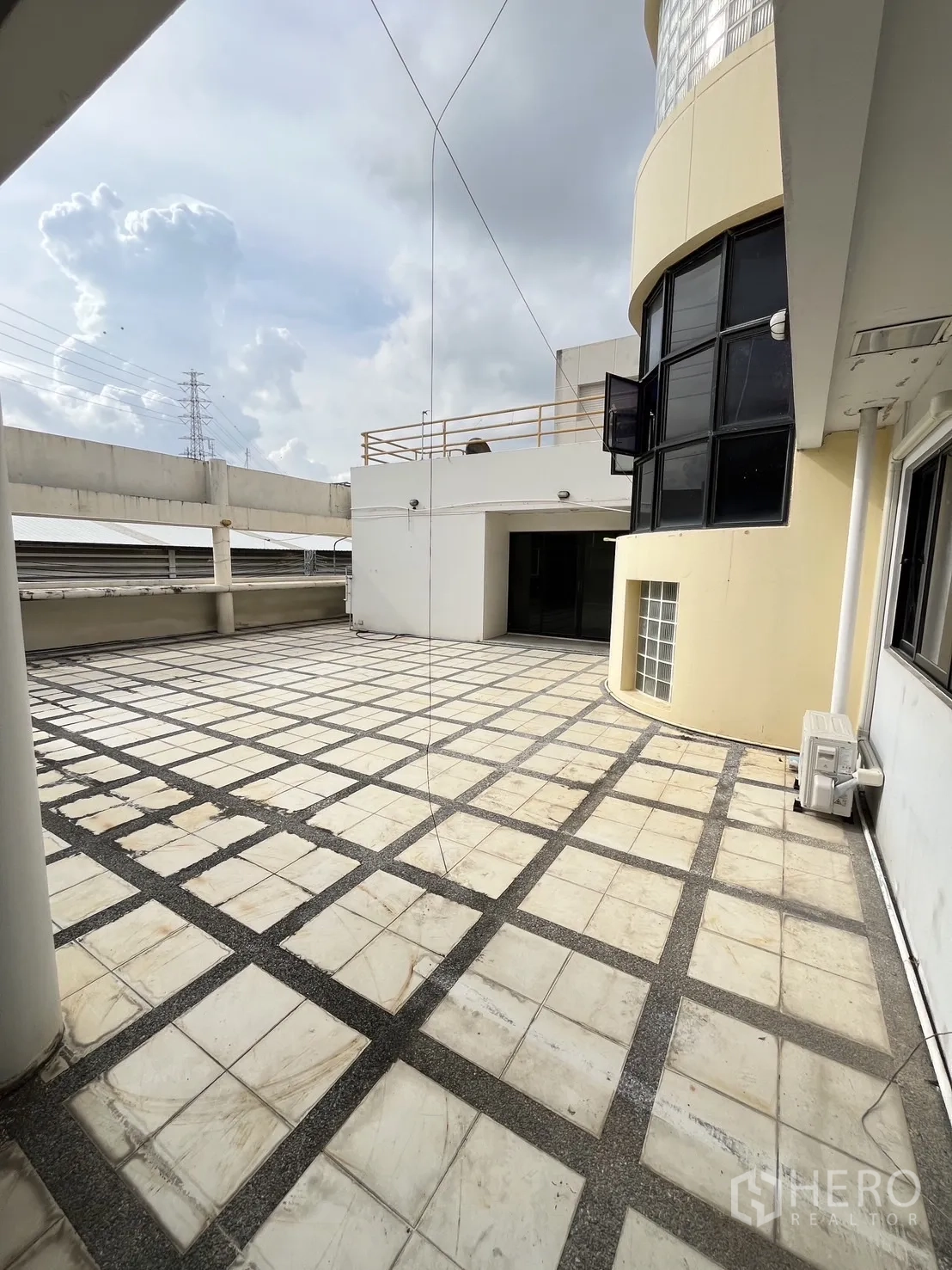 Warehouse for rent in Huai Khwang, Bangkok - Rooftop terrace with tiled deck and the building’s curved facade.